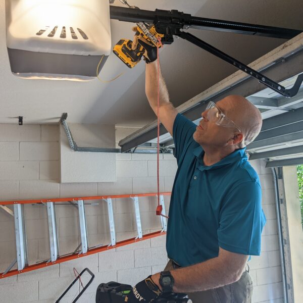 Certified Garage Door Technician from Rocket Estate Builders servicing an older garage door opener in Central Florida