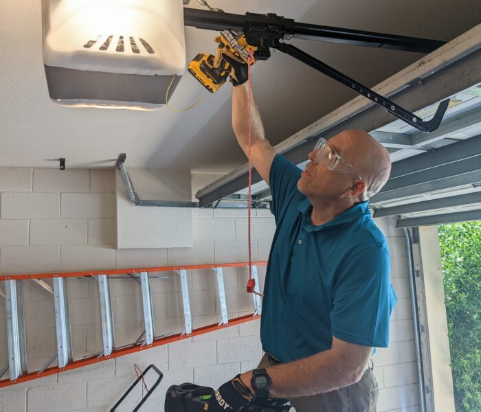 Certified Garage Door Technician from Rocket Estate Builders servicing an older garage door opener in Central Florida